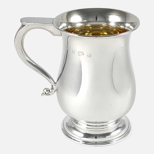the sterling silver mug viewed side on with handle pointing towards the left