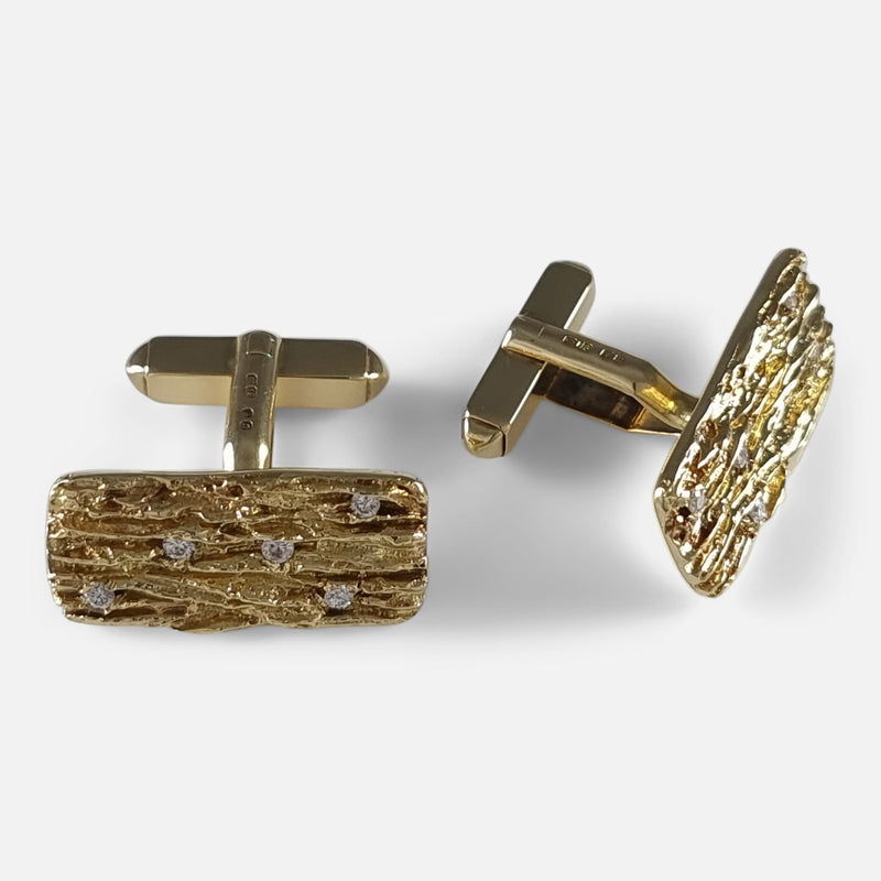 Viewing from directly above: left cufflink faces forward, right cufflink markedly angled to the right, showcasing intricate design details.