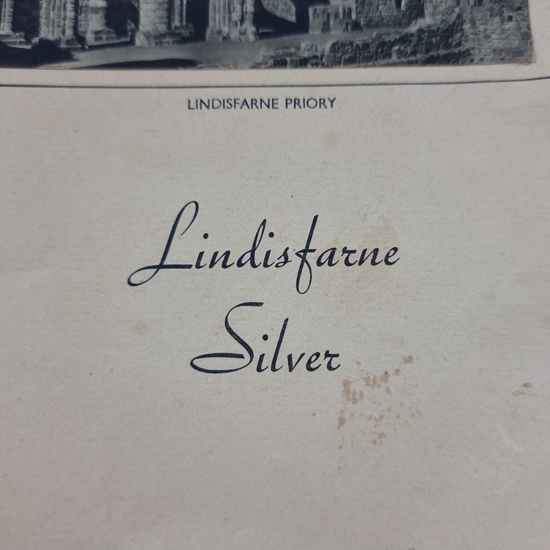 focused on the 'Lindisfarne Silver' text to the front cover of the booklet included with salver