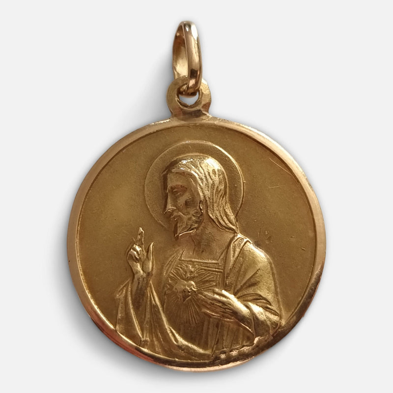 a depiction of the sacred heart of Jesus to one side of the pendant