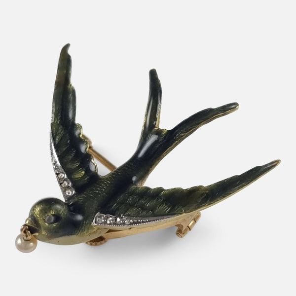 the 18ct gold pearl, diamond, and enamel swallow brooch viewed at a slight angle