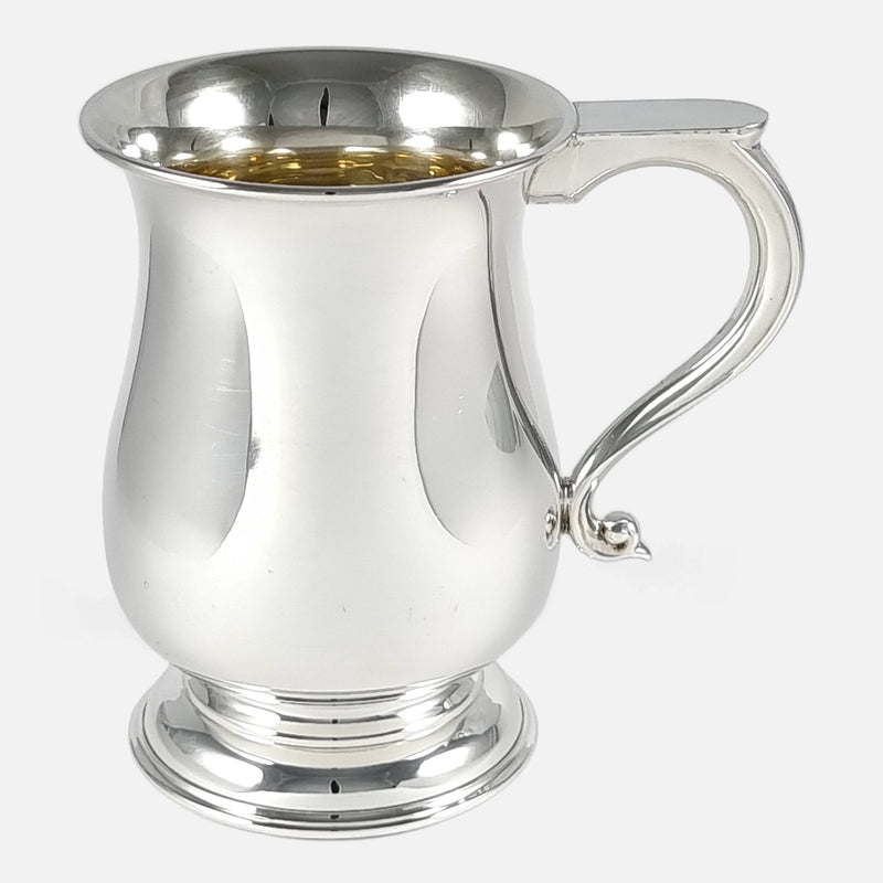 the silver mug viewed side on with handle pointing towards the right