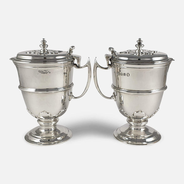 The pair of sterling silver ewers facing in opposite directions