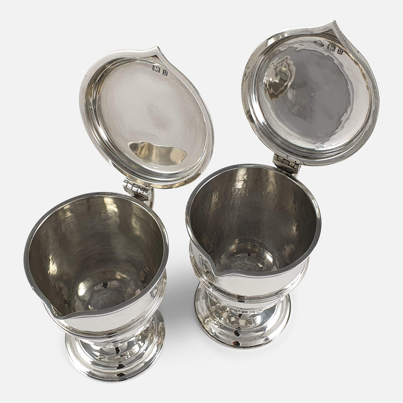 a view of inside the silver jugs with lids raised open