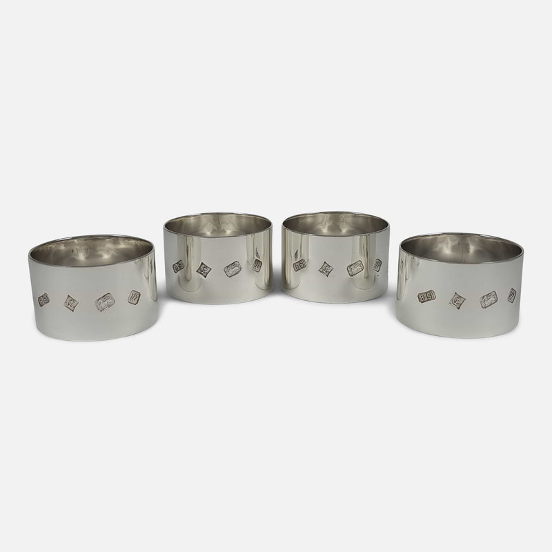 the set of four sterling silver napkin rings laid out in a crescent formation