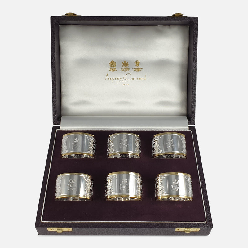 Set of six parcel gilt Britannia standard silver napkin rings viewed in a case