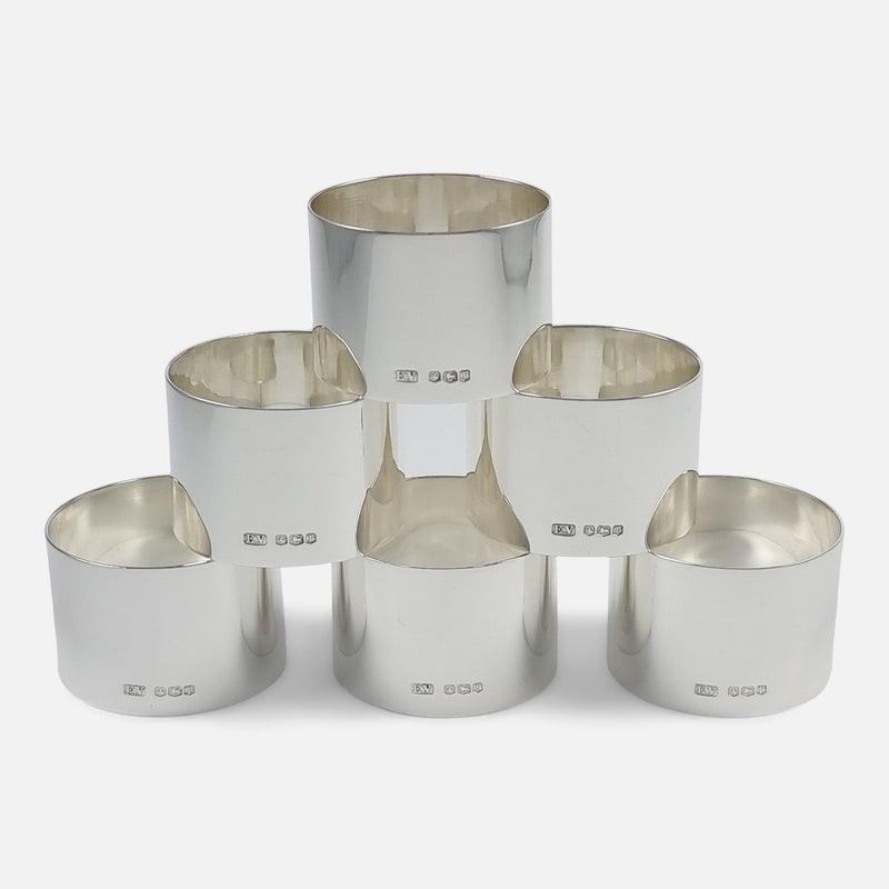 the set of sterling silver napkin rings viewed stacked in pyramid form with hallmarks to the forefront