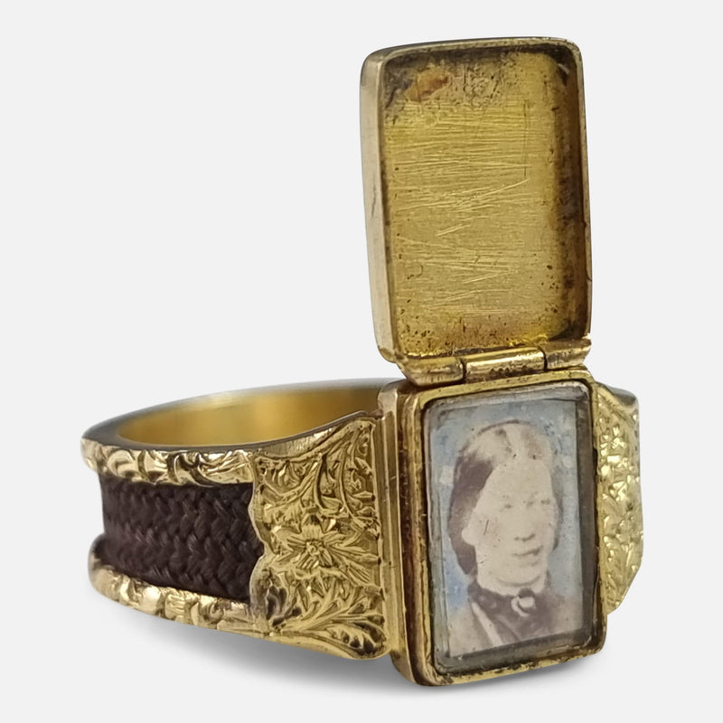 the ring viewed at angle with hinged cover opened to reveal the portrait of a Victorian woman