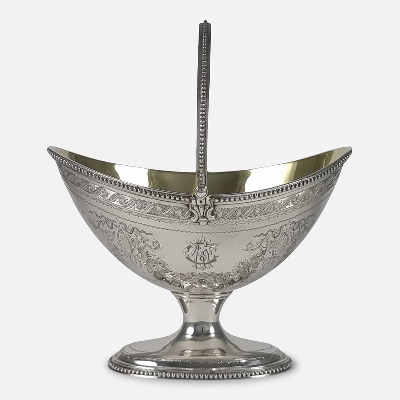 the Victorian sterling silver swing-handled sugar basket viewed side on with engraved cartouche to the forefront