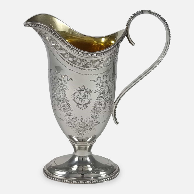the Victorian sterling silver cream jug viewed side on with engraved cartouche to the forefront